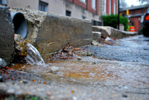 A pipe spills stormwater onto pavement