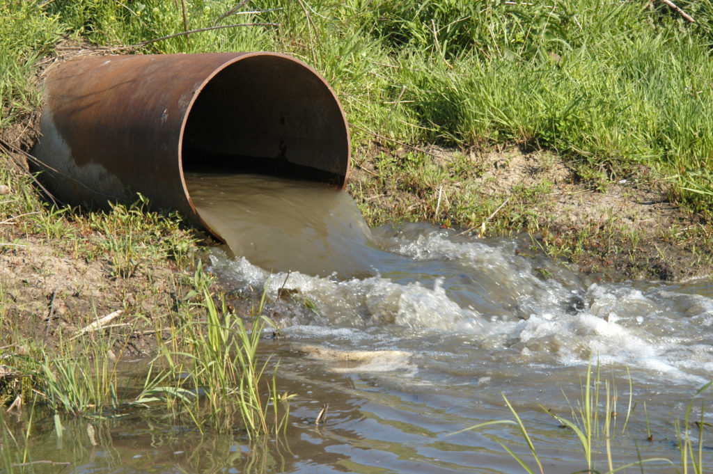 Dirty water is flowing from a pipe into a water body