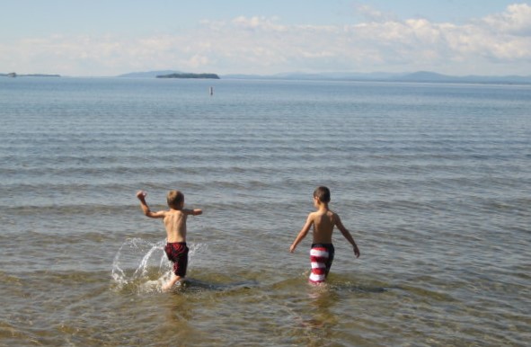 boys play in shallow water at the edge of a lake