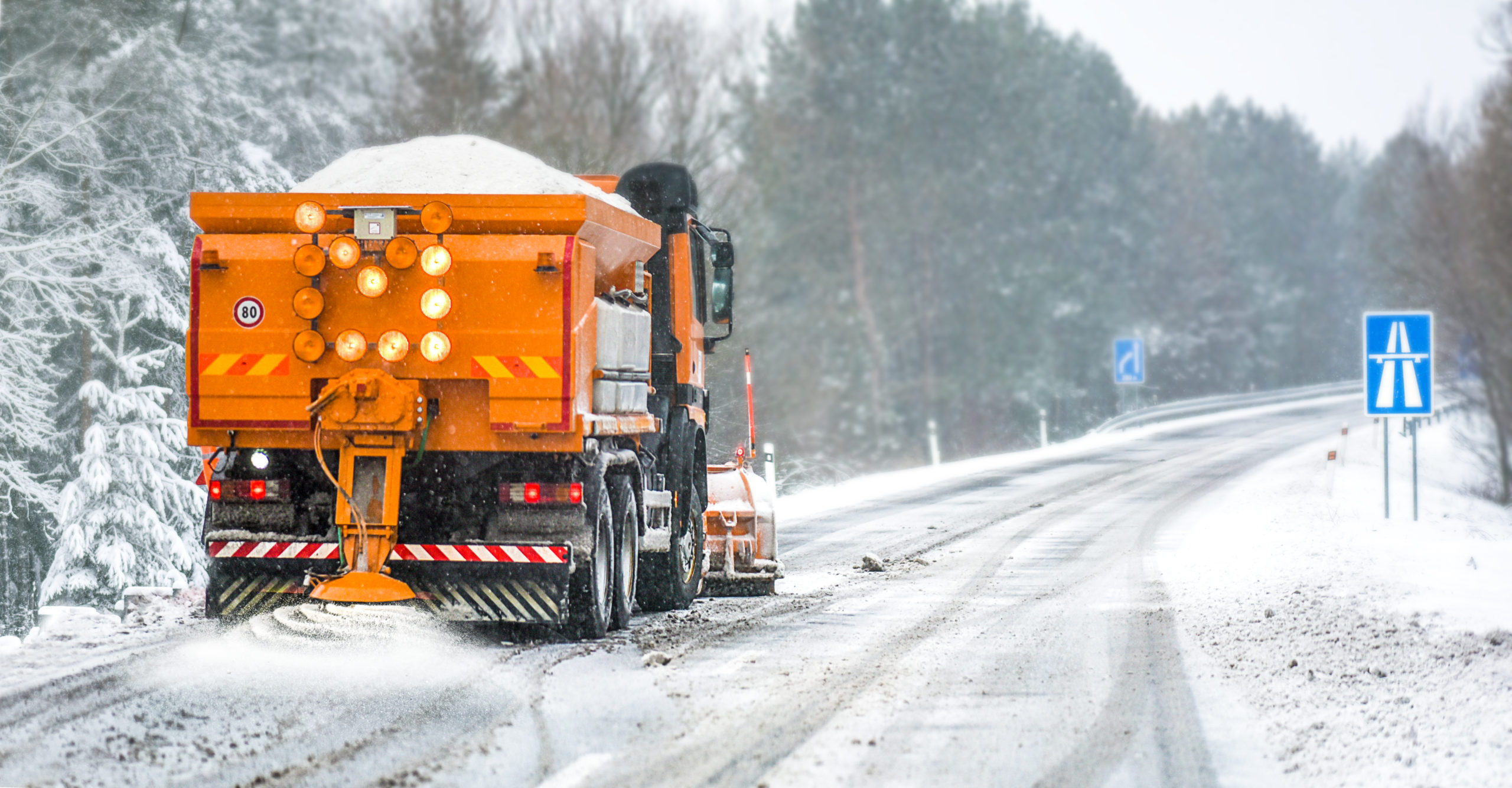 Truck applying salt to a snowy road. 