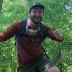 Profile of NEIWPCC's James Plummer, hiking in the woods giving a thumbs up.