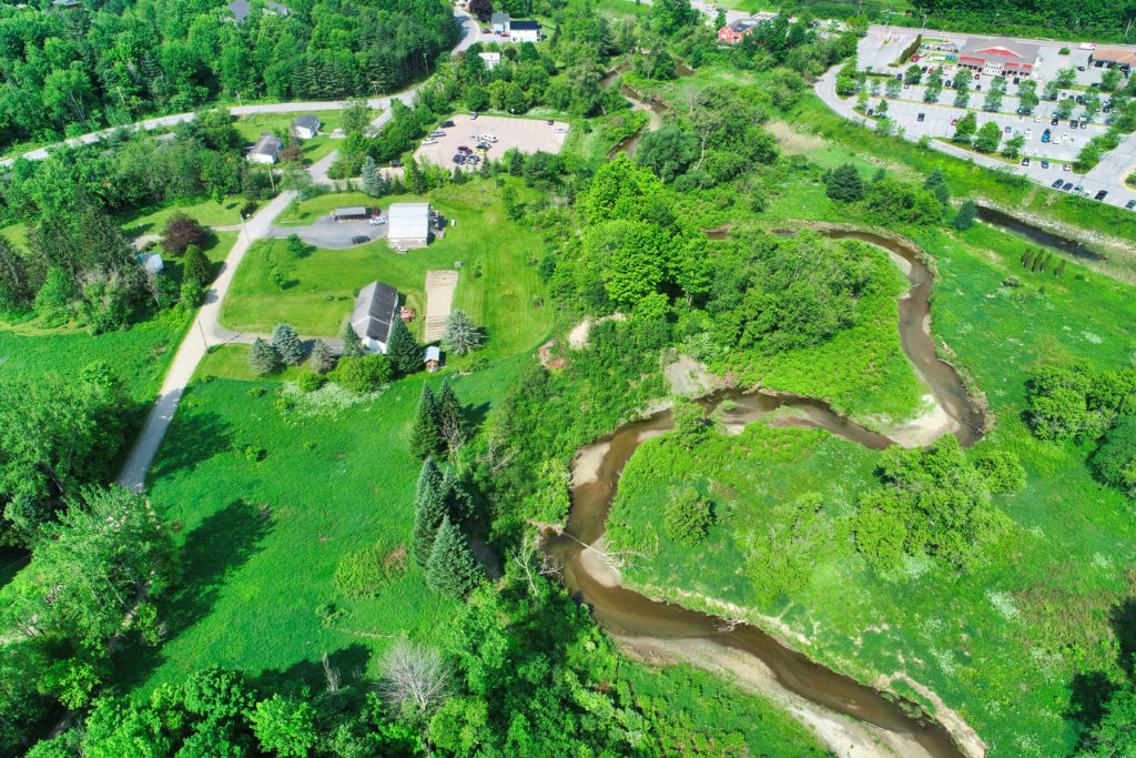 Aerial photo of a Vermont stream with a house nearby.