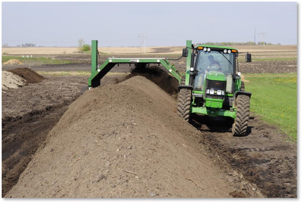 Biosolids being composted with a green tractor
