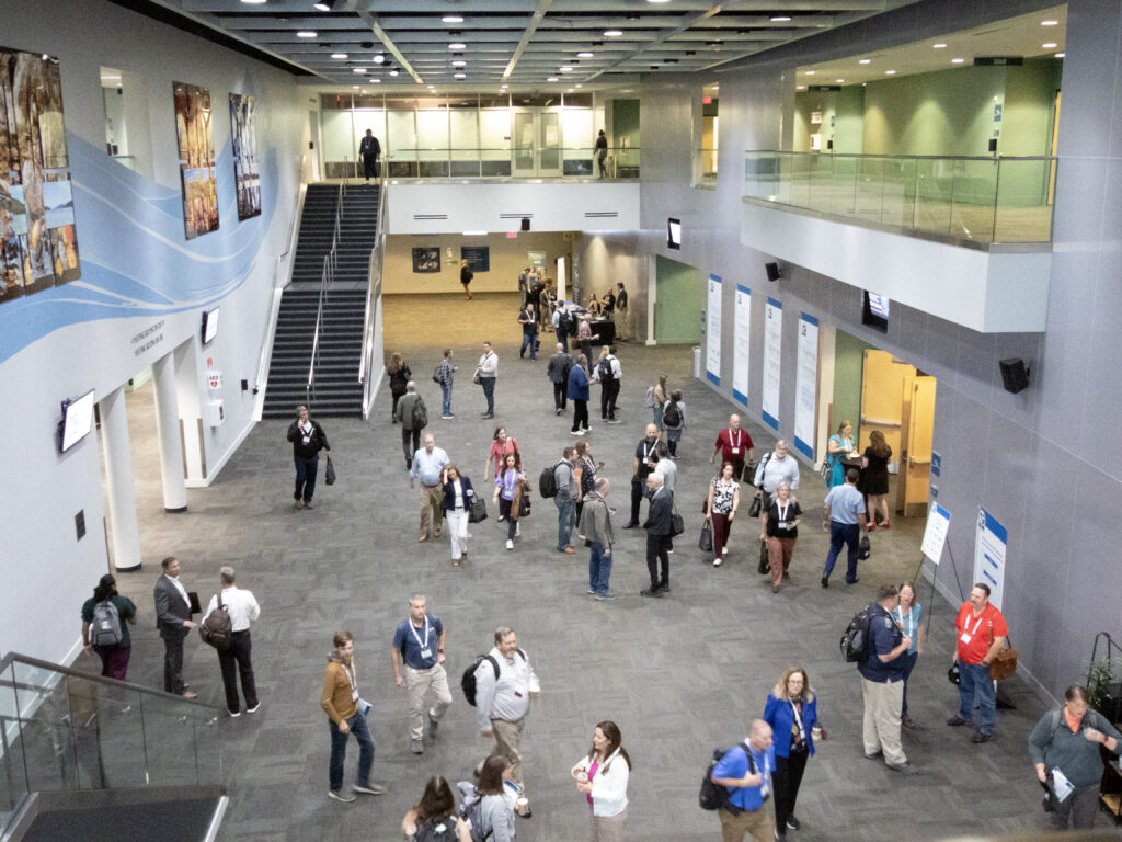 An image looking down from the second floor of conference participants chatting and networking in the conference venue.