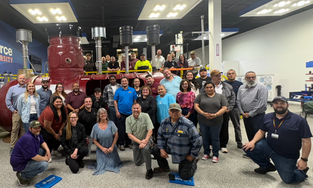 A group of people smiling for the camera in front of an underground storage tank.