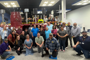 A group of people smiling for the camera in front of an underground storage tank.